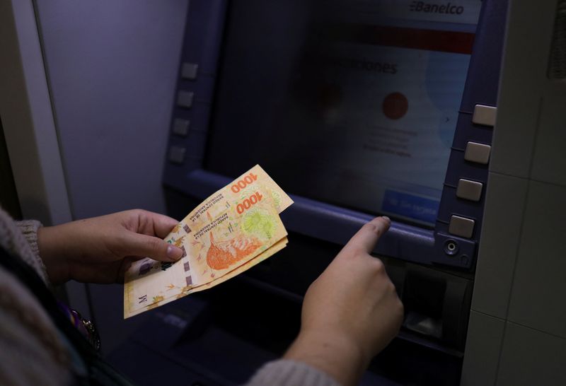 &copy; Reuters. FILE PHOTO: A woman withdraws cash from an atm, as Argentine peso bill continues to devalue by years of inflation, meaning people need to carry huge wads of cash, in Buenos Aires, Argentina May 23, 2022. REUTERS/Cristina Sille  