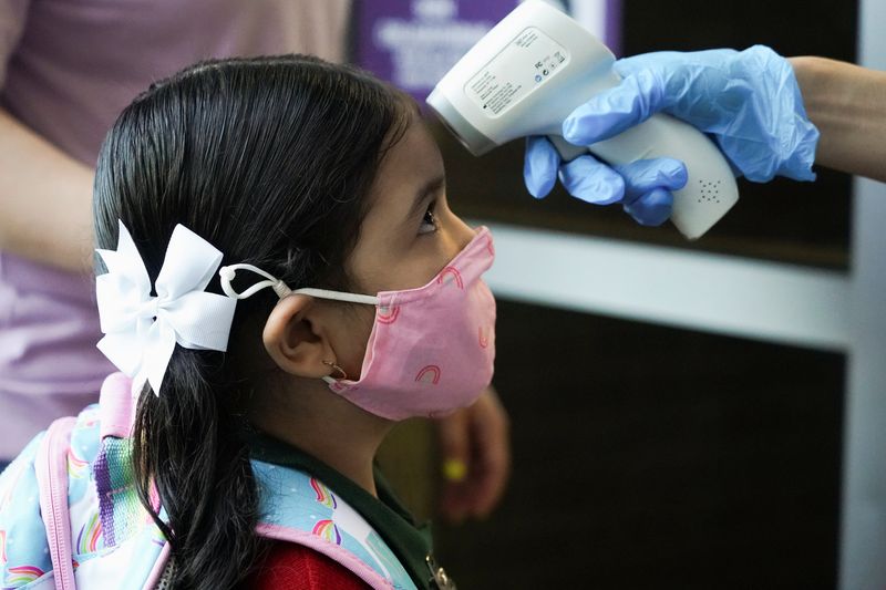 © Reuters. FILE PHOTO: A Pre-K student has her temperature checked before entering Benbrook Elementary School on the first day of school amid the coronavirus disease (COVID-19) pandemic in Houston, Texas, U.S., August 23, 2021.  REUTERS/Go Nakamura/File Photo 
