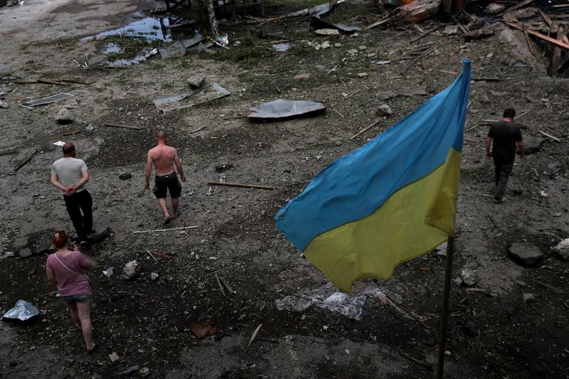 &copy; Reuters. عمال يعاينون الأضرار التي لحقت بمخزن للأخشاب بعد هجوم على مشارف مدينة خاركيف في شرق أوكرانيا يوم الجمعة. تصوير: إيفان ألفارادو - رويترز.