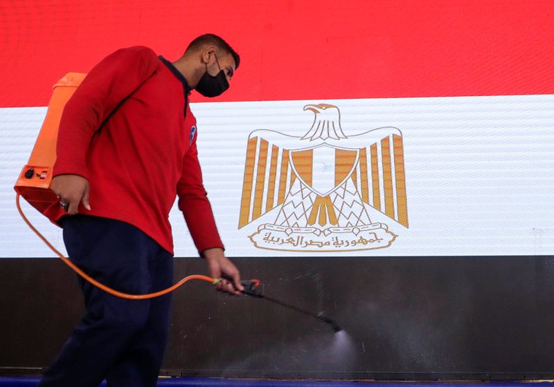 &copy; Reuters. FILE PHOTO: An employee sprays disinfectant as a precautionary measure amid the coronavirus disease (COVID-19) pandemic in front of Egyptian national flag at the State Council headquarters in Giza, Egypt October 19, 2021. REUTERS/Mohamed Abd El Ghany