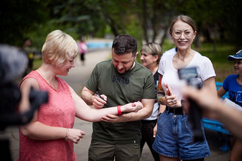 &copy; Reuters. الرئيس الأوكراني فولوديمير زيلينسكي يوقع على ذراع امرأة من أنصاره في زابوريجيا يوم الأحد. صورة لرويترز من المكتب الصحفي للرئاسة الأوكرانية