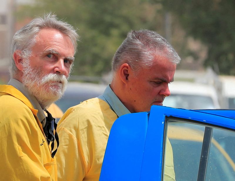 © Reuters. FILE PHOTO: Jim Fitton from Britain and Volker Waldmann from Germany, who are suspected of smuggling ancient artefacts out of Iraq, are escorted in handcuffs by Iraqi policemen, outside a court in Baghdad, Iraq, May 22, 2022. REUTERS/Thaier Al-Sudani/File Photo