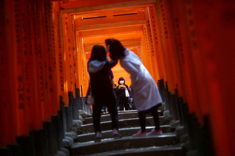 &copy; Reuters. FOTO DE ARCHIVO. Visitantes, con mascarillas tras el brote de la enfermedad del coronavirus (COVID-19), exploran las puertas torii de madera del santuario sintoísta Fushimi Inari Taisha en Kioto, Japón. 13 de marzo de 2020. REUTERS/Edgard Garrido