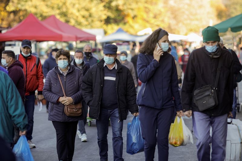 &copy; Reuters. FILE PHOTO: People wearing protective masks walk in a market, following the introduction of new restrictions imposed by the government after a surge in coronavirus disease (COVID-19) cases in Bucharest, Romania, October 26, 2021. Inquam Photos/George Cali