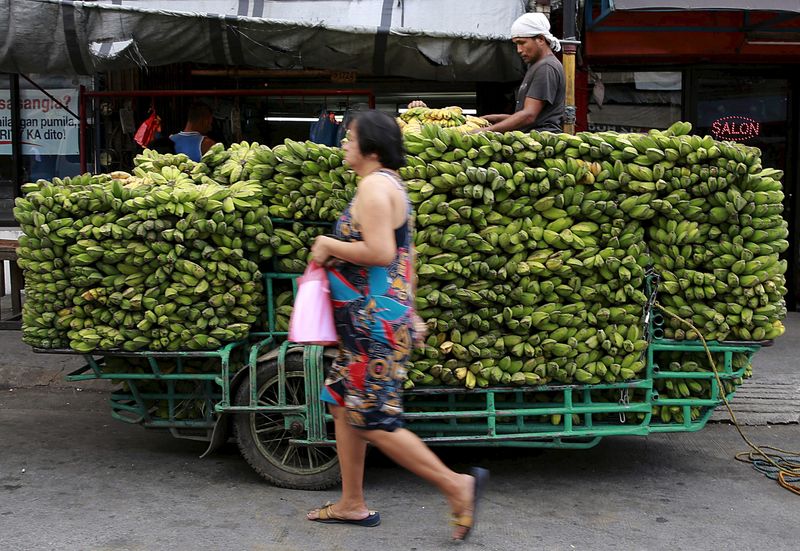 &copy; Reuters. A woman walks past a worker unloading bananas from a motorcycle cab, which will be delivered to a nearby wet market, in Manila July 21, 2015. REUTERS/Romeo Ranoco/File Photo