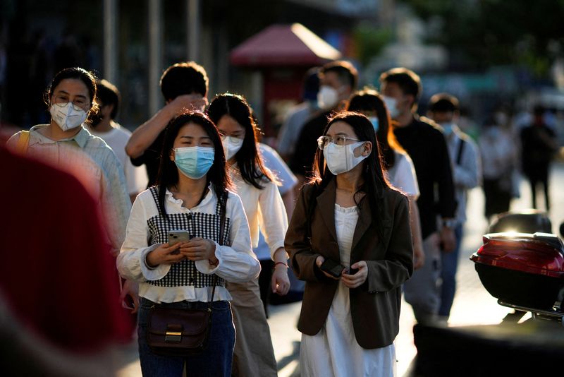 &copy; Reuters. Des employés de bureau portant des masques de protection marchent dans une rue de Shanghaï. Après deux mois de strictes restrictions sanitaires visant à contenir la propagation du coronavirus, Shanghaï cherche à redonner confiance aux entreprises mu