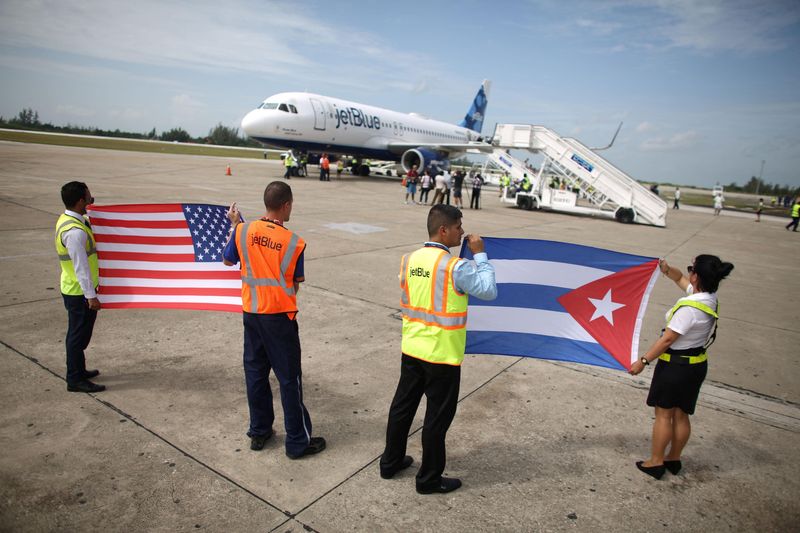 &copy; Reuters. FOTO DE ARCHIVO: Personal de tierra sostiene banderas de Estados Unidos y Cuba cerca de un avión de JetBlue recién aterrizado, el primer vuelo comercial regular entre Estados Unidos y Cuba en más de 50 años, en el Aeropuerto Internacional Abel Santama