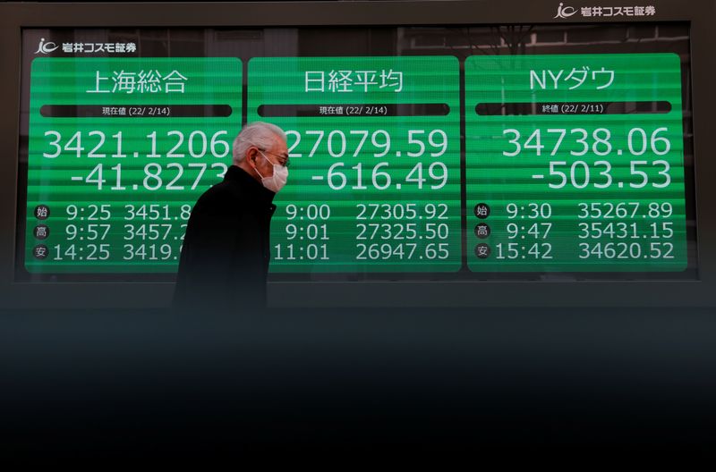 &copy; Reuters. FOTO DE ARCHIVO. Un hombre pasa junto a una pantalla que muestra índices en Tokio, Japón