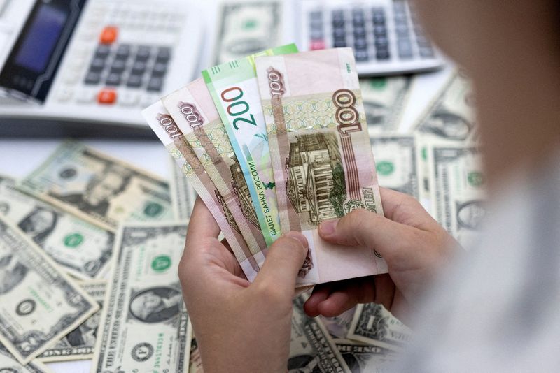 &copy; Reuters. FILE PHOTO: A woman holds Russian Roubles in front of U.S. Dollar banknotes in this illustration taken May 30, 2022. REUTERS/Dado Ruvic/Illustration