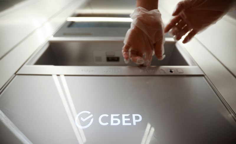 &copy; Reuters. FILE PHOTO: A woman wearing protective gloves uses an ATM machine in an office of the Russian largest lender Sberbank in Moscow, Russia December 24, 2020. REUTERS/Maxim Shemetov