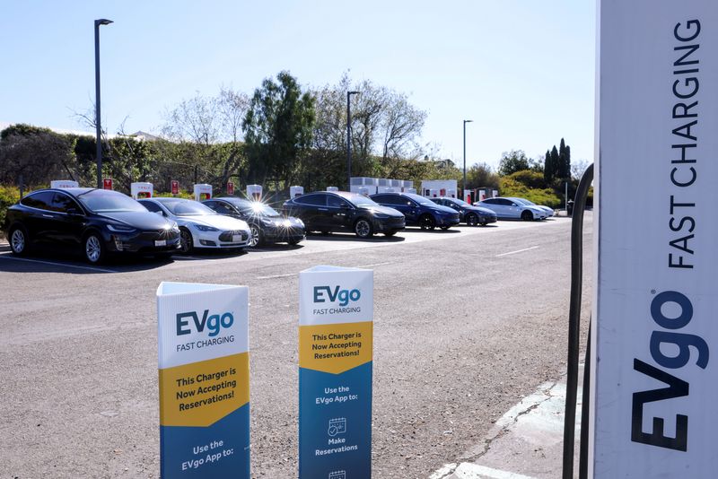&copy; Reuters. FILE PHOTO: People charge their electric cars at a Tesla super charging station next to an EVgo electric charging location in Carlsbad, California, U.S., March 7, 2022. REUTERS/Mike Blake
