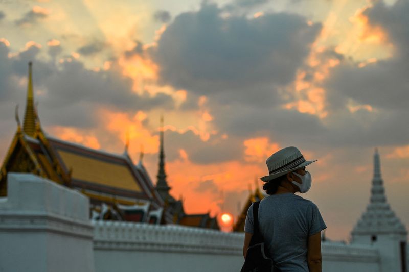 &copy; Reuters. FILE PHOTO: A tourist wears a face mask to prevent spread of the coronavirus disease (COVID-19) during sunset near the Grand Palace in Bangkok, Thailand, January 7, 2022. REUTERS/Chalinee Thirasupa