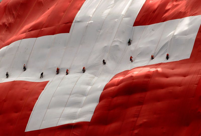 © Reuters. FILE PHOTO: Climbers are seen on a huge 80x80 metres (262x262 feet) Swiss national flag after fixing it on the western face of the north-eastern Swiss landmark Mount Saentis, Switzerland July 31, 2018.  REUTERS/Arnd Wiegmann/File Photo
