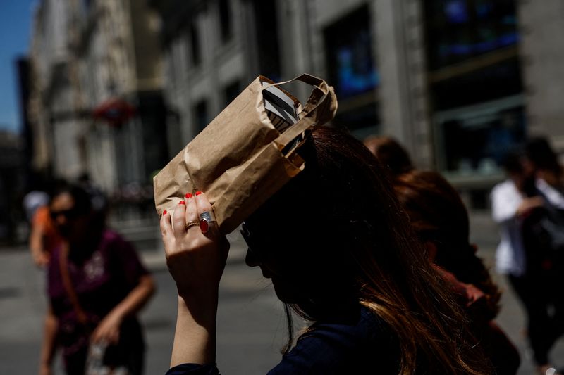 &copy; Reuters. A woman covers her head with a bag during a hot day as Spain braces for a heatwave in Madrid, Spain, June 10, 2022. REUTERS/Susana Vera