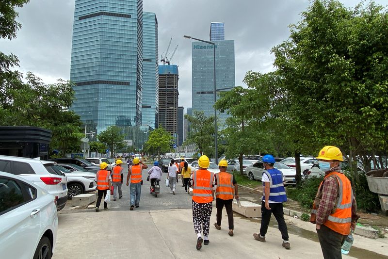 © Reuters. Construction workers walk past office buildings in Shenzhen's Nanshan district, Guangdong province, China June 10, 2022. REUTERS/David Kirton