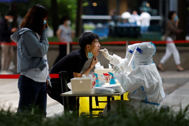 &copy; Reuters. أحد العالمين في القطاع الطبي يرتدي بدلة واقية يأخذ مسحة من أحد الأشخاص خلال اختبار جماعي للإصابة بفيروس كورونا في أحد مقاطعات بكين يوم الاث