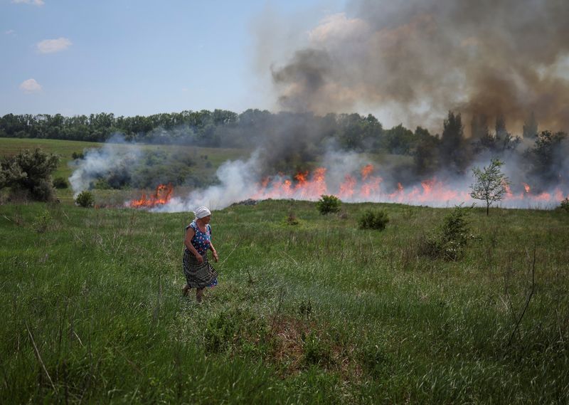 &copy; Reuters. Un residente local mira la hierba que está en llamas después de un bombardeo, en medio del ataque de Rusia a Ucrania, cerca de la ciudad de Bakhmut, región de Donetsk Ucrania. 12 de junio de 2022. REUTERS/Gleb Garanich