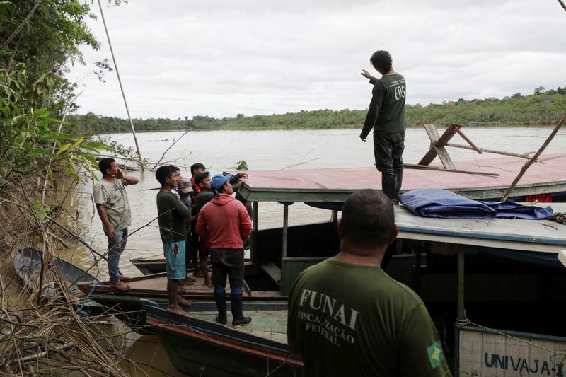 &copy; Reuters. FILE PHOTO: Indigenous people helping rescuers stand on a boat during the search operation for British journalist Dom Phillips and indigenous expert Bruno Pereira, who went missing while reporting in a remote and lawless part of the Amazon rainforest, nea
