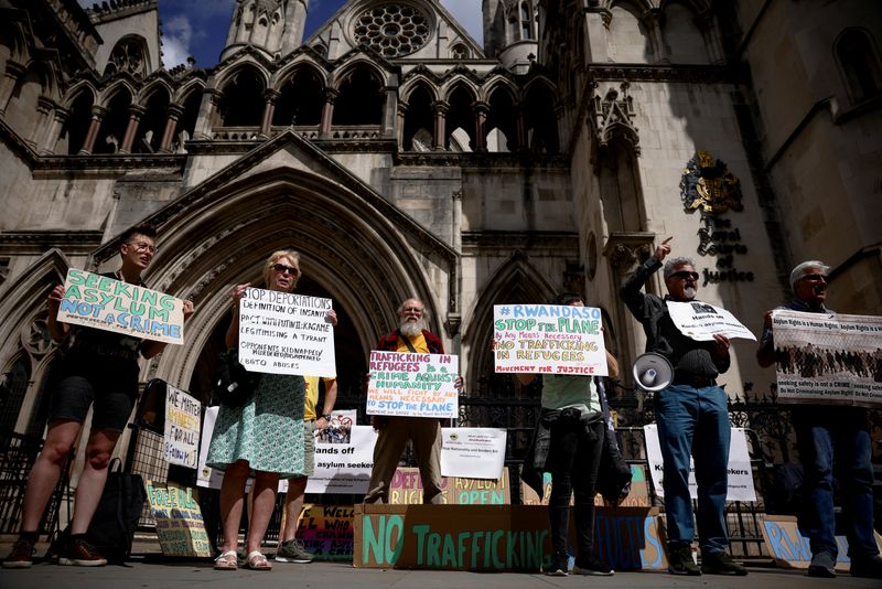 &copy; Reuters. Demonstrators display placards during a protest outside the Royal Courts of Justice whilst a legal case is heard over halting a planned deportation of asylum seekers from Britain to Rwanda, in London, Britain, June 13, 2022. REUTERS/Henry Nicholls