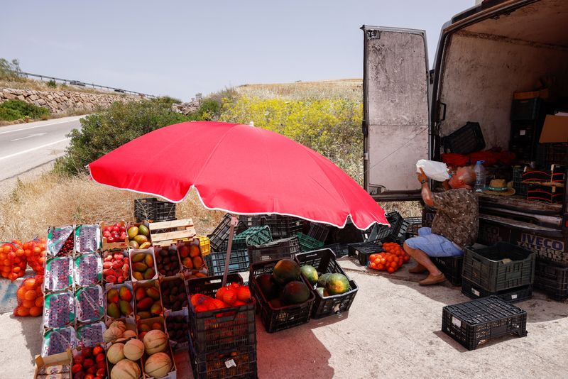 &copy; Reuters. A fruit and vegetable vendor drinks water to cool off, under the strong sun, as he waits for customers, during the first heatwave of the year in Ardales, Spain, June 13, 2022. REUTERS/Jon Nazca