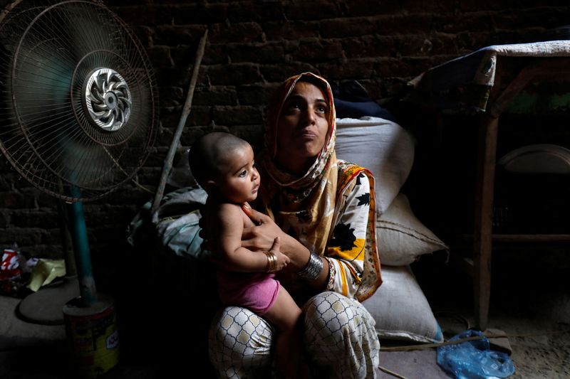© Reuters. Razia, 25, and her six-month-old daughter Tamanna, sit in front of a fan to cool off during a heatwave, in Jacobabad, Pakistan, May 15, 2022. Last month Jacobabad became the hottest city on Earth. Women are especially vulnerable to rising temperatures in poor countries on the frontlines of climate change because many have little choice but to work through their pregnancies and soon after giving birth, according to interviews with more than a dozen female residents in the Jacobabad area as well as half a dozen development and human rights experts.  REUTERS/Akhtar Soomro  