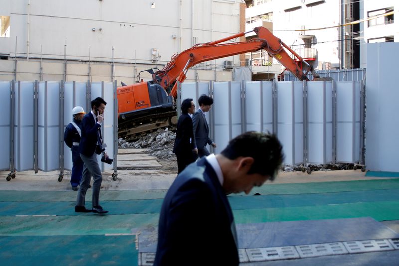 &copy; Reuters. FILE PHOTO: Businessmen walk past heavy machinery at a construction site in Tokyo's business district, Japan, January 16, 2017.    REUTERS/Toru Hanai/