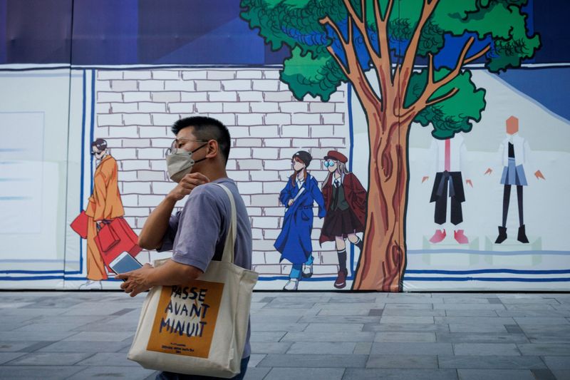&copy; Reuters. رجل يسير بجوار متجر للتجزئة مغلق بألواح خشبية في منطقة تسوق مع استمرار تفشي وباء فيروس كورونا في بكين يوم الثلاثاء. تصوير: توماس بيتر - رويتر