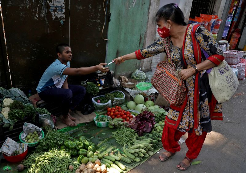 &copy; Reuters. FILE PHOTO: Indrani Majumder, a consumer, buys vegetables from a roadside vegetable vendor in Kolkata, India, March 22, 2022. Picture taken March 22, 2022. REUTERS/Rupak De Chowdhuri