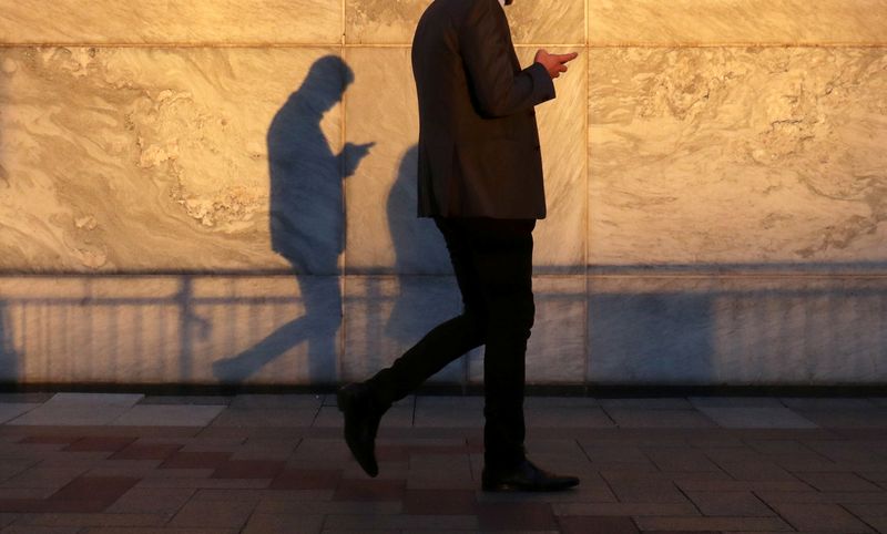 &copy; Reuters. FILE PHOTO: An unidentified man using a smart phone walks through London's Canary Wharf financial district in the evening light in London, Britain, September 28, 2018.   REUTERS/Russell Boyce