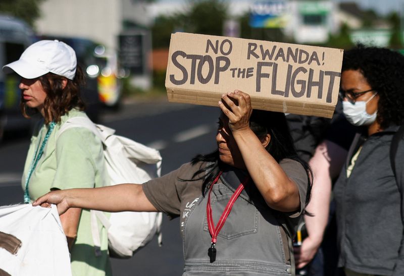 &copy; Reuters. Una activista que bloquea una calle que sale del Centro de Expulsión de Inmigrantes de Colnbrook sostiene una pancarta durante una protesta contra los planes del Gobierno británico de deportar a solicitantes de asilo a Ruanda, cerca del aeropuerto de He