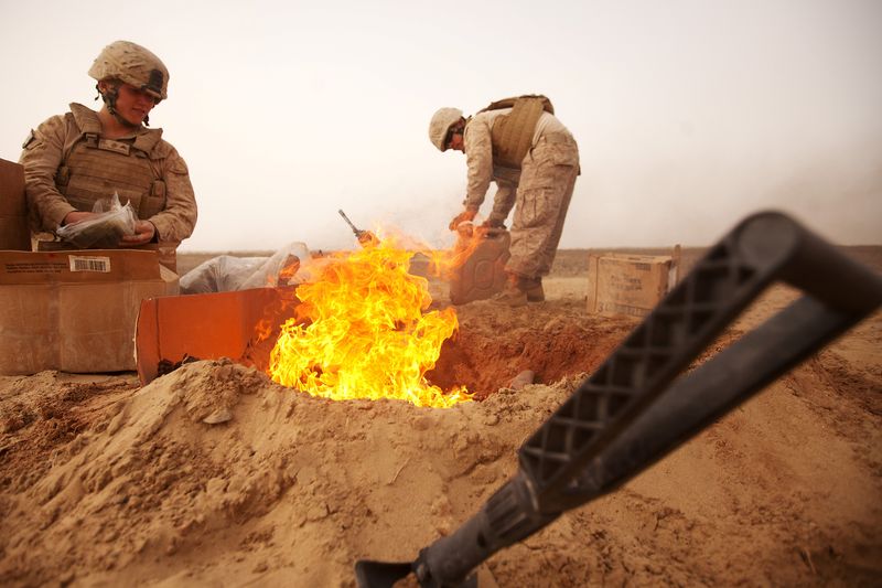 &copy; Reuters. FILE PHOTO: U.S. Marines dispose of trash in a burn pit while stopping for a sandstorm to pass during a convoy to Patrol Base Sre Kalad in Khan Neshin District, Afghanistan March 3, 2012. Picture taken March 3, 2012. Cpl. Alfred V. Lopez/U.S. Marines/Hand