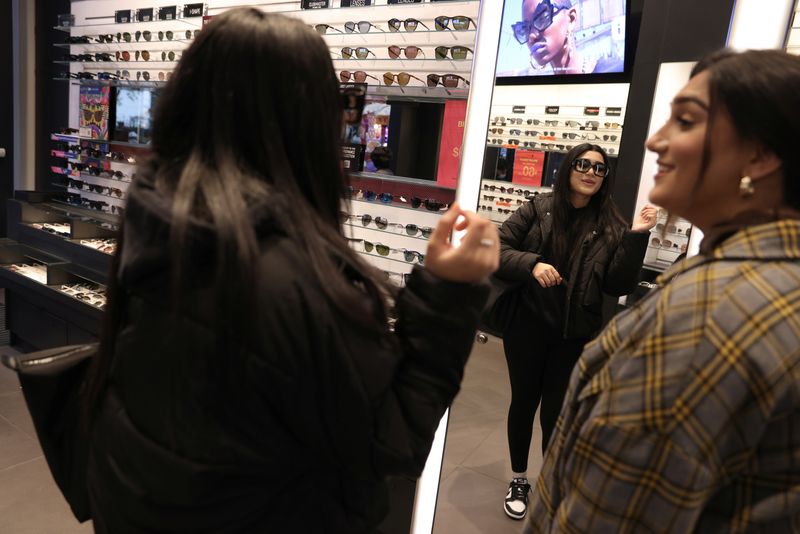 &copy; Reuters. FILE PHOTO: People try sunglasses in a Sunglass Hut store, a brand owned by EssilorLuxottica SA, in Manhattan, New York City, U.S., November 30, 2021. REUTERS/Andrew Kelly