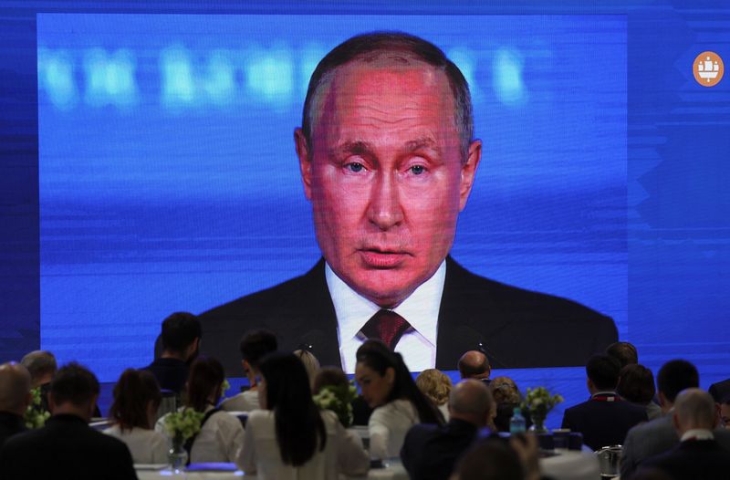 © Reuters. Participants gather near a screen showing Russian President Vladimir Putin, who delivers a speech at the St. Petersburg International Economic Forum (SPIEF) in Saint Petersburg, Russia June 17, 2022. REUTERS/Anton Vaganov