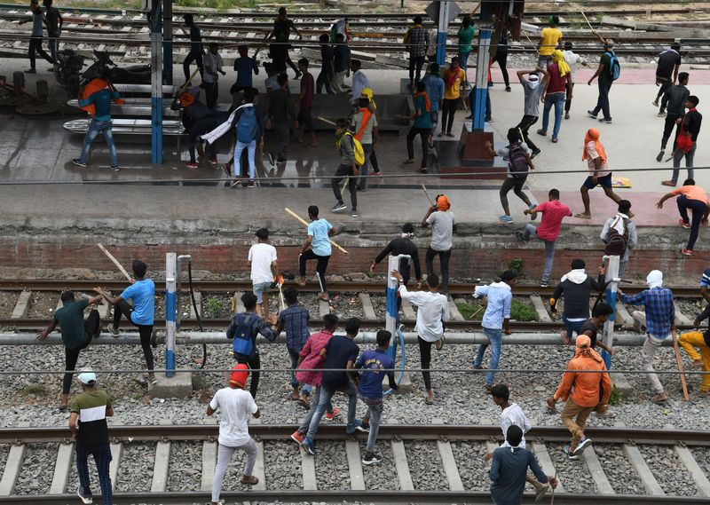 &copy; Reuters. متظاهرون يحملون العصي ويركضون في محطة سكة حديد خلال احتجاج على "نظام أجنيباث" لتجنيد أفراد للقوات المسلحة في ولاية بيهار شرقي الهند يوم الجم