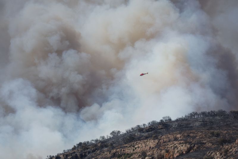 © Reuters. Un helicóptero vuela cerca del humo durante un incendio forestal cerca de Artesa de Segre, España, Junio 18, 2022. REUTERS/Albert Gea