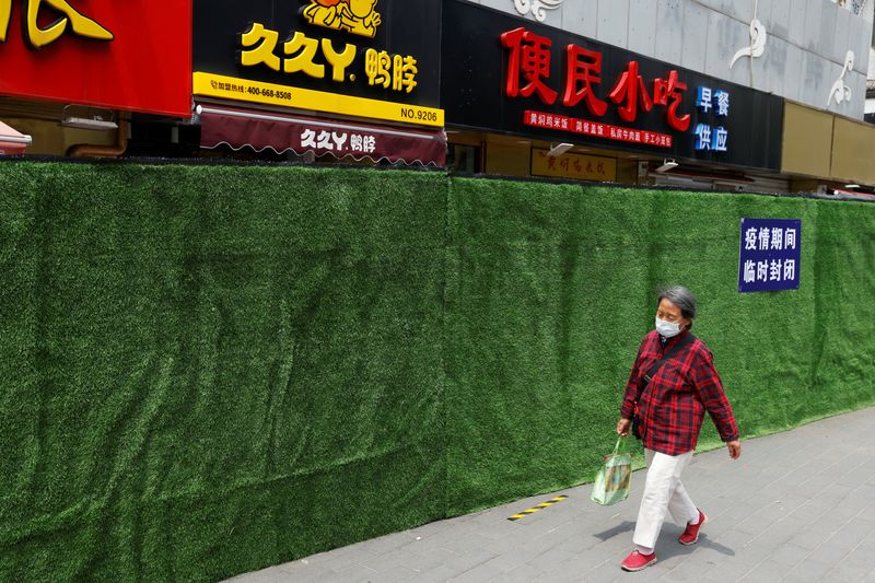 &copy; Reuters. امرأة تضع كمامة تسير في أحد أحياء بكين يوم 13 يونيو حزيران 2022. تصوير: كارلوس جارسيا راولينز - رويترز