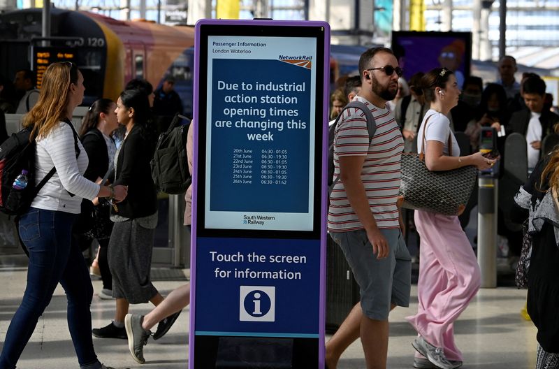 &copy; Reuters. Des passagers passent devant un panneau d'information sur les grèves  à la gare de Waterloo. Une grève des cheminots britanniques débute pour protester contre le gel des salaires et des suppressions d'emplois. /Photo prise le 20 juin 2022/REUTERS/Toby