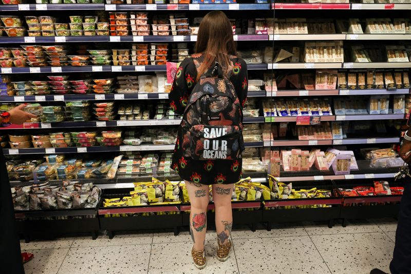 &copy; Reuters. FILE PHOTO: A person wearing a backpack with the slogan "SAVE OUR OCEANS", looks at food goods in a shop as UK inflation heads towards 10% in London, Britain, June 16, 2022.   REUTERS/Kevin Coombs