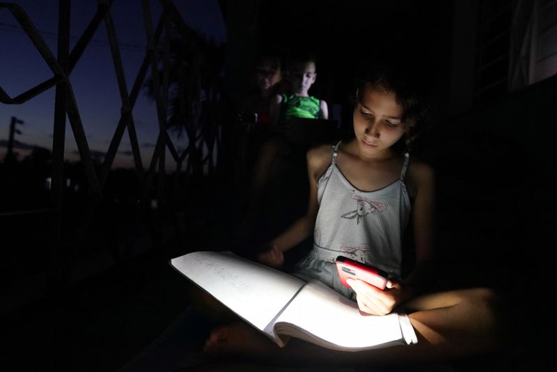 &copy; Reuters. Emily Villega, de 10 años, hace sus deberes usando la luz de un teléfono móvil en el balcón de su casa durante un apagón en Guanajay, Cuba. 17 de junio de 2022.  REUTERS/Alexandre Meneghini