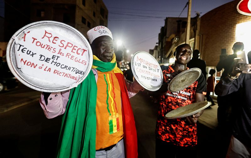 &copy; Reuters. Ibrahima Soumare, 47, a supporter of Senegal's main opposition coalition Yewwi Askan Wi holds signs glued on pot lids during a protest over the disqualification of their national list for the July 31 legislative election in Dakar, Senegal, June 22, 2022. 