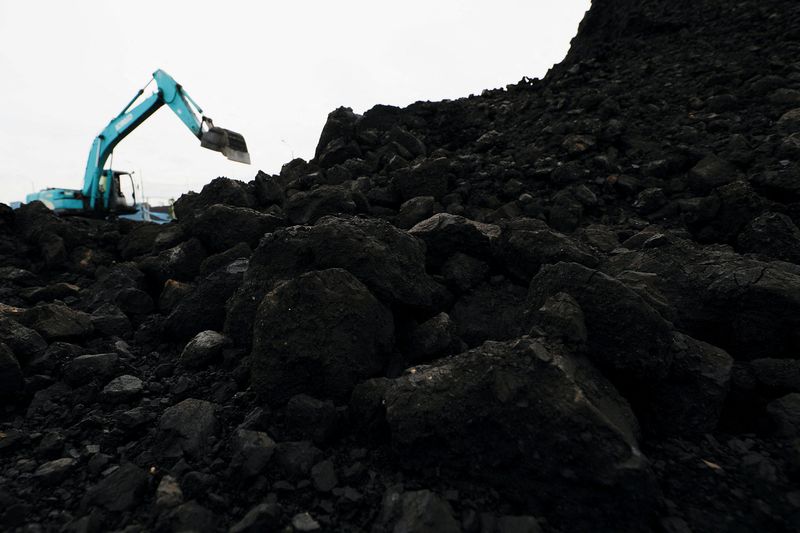 &copy; Reuters. 　６月２３日、インドネシア財務省当局者は、世界経済の状況などを考慮し、来月予定の炭素税導入を再延期する可能性があると述べた。写真は重機ではしけからトラックへと積み下ろされ