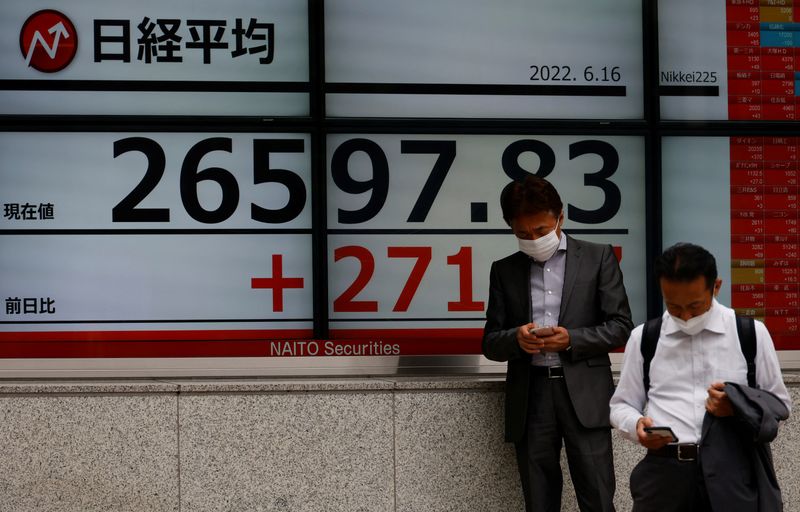 &copy; Reuters. يابانيان يستخدمون هواتفهم المحمولة أمام شاشة إلكترونية تعرض حركة مؤشر نيكي الياباني خارج شركرة سمسرة في طوكيو يوم 17 يونيو حزيران 2022. تصوير: 