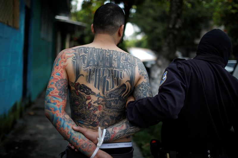 &copy; Reuters. فرد شرطة يعتقل رجلا من العصابة الإجرامية الدولية إم إس-13 في السلفادور. صورة من أرشيف رويترز.