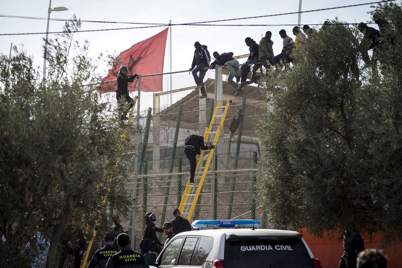 &copy; Reuters. مهاجرون أفارقة يقفون يحاولون عبور سياج حدودي من المغرب إلى جيب مليلية الإسباني عام 2015. صورة من أرشيف رويترز 