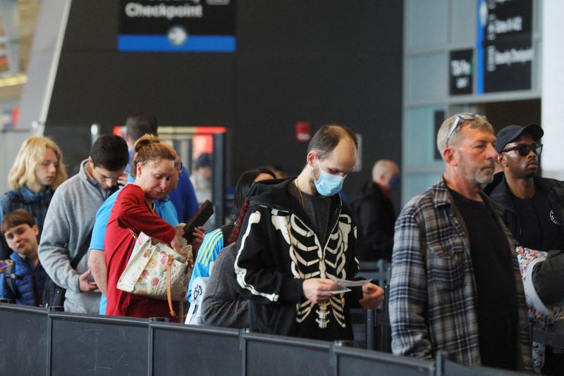 &copy; Reuters. FILE PHOTO: Travellers wearing masks and not wearing masks wait in line at a security checkpoint at Logan International Airport in Boston, Massachusetts, U.S., April 19, 2022.   REUTERS/Brian Snyder/File Photo