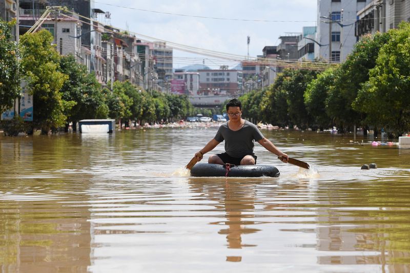 &copy; Reuters. رجل يجلس على شيء طاف ويجدف وسط المياه التي غمرت أحد الشوارع جراء الأمطار الغزيرة في إقليم قوانغدونغ بالصين يوم 23 يونيو حزيران 2022. صورة لرويت