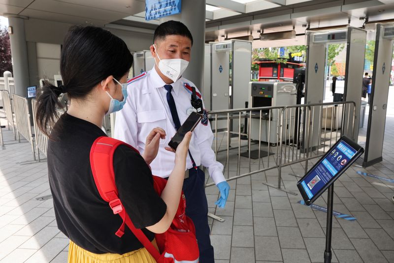 &copy; Reuters. FOTO DE ARCHIVO: Un guardia de seguridad con mascarilla comprueba el resultado de un test de COVID-19 de una turista a la entrada de un parque de atracciones de Universal Studios en Pekín, China, el 25 de junio de 2022. REUTERS/Tingshu Wang