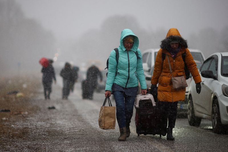 &copy; Reuters. FOTO DE ARCHIVO: Personas que huyen de la operación militar de Rusia contra Ucrania caminan hacia el paso fronterizo de Shehyni hacia Polonia pasando por delante de los coches que esperan en la cola para cruzar la frontera, a las afueras de Mostyska, Ucr