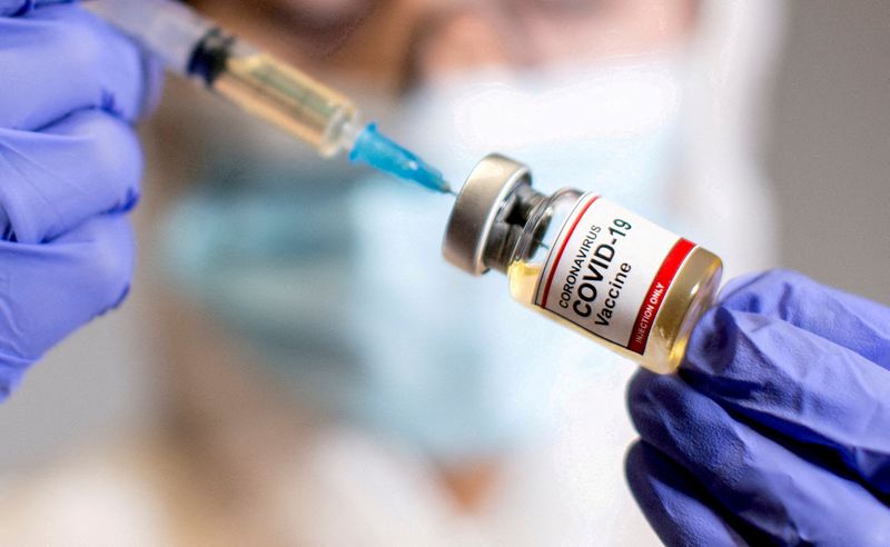 &copy; Reuters. FILE PHOTO: A woman holds a small bottle labelled with a "Coronavirus COVID-19 Vaccine" sticker and a medical syringe in this illustration taken  October 30, 2020. REUTERS/Dado Ruvic/File Photo