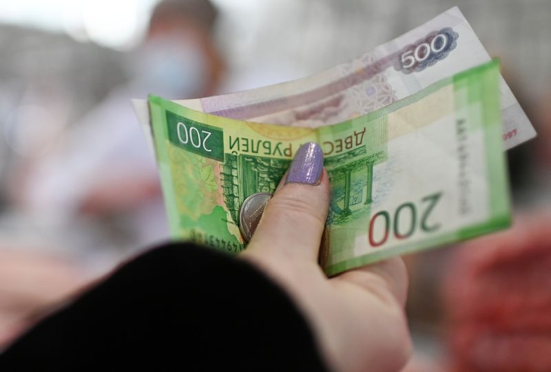 &copy; Reuters. A customer hands over Russian rouble banknotes and coins to a vendor at a market in Omsk